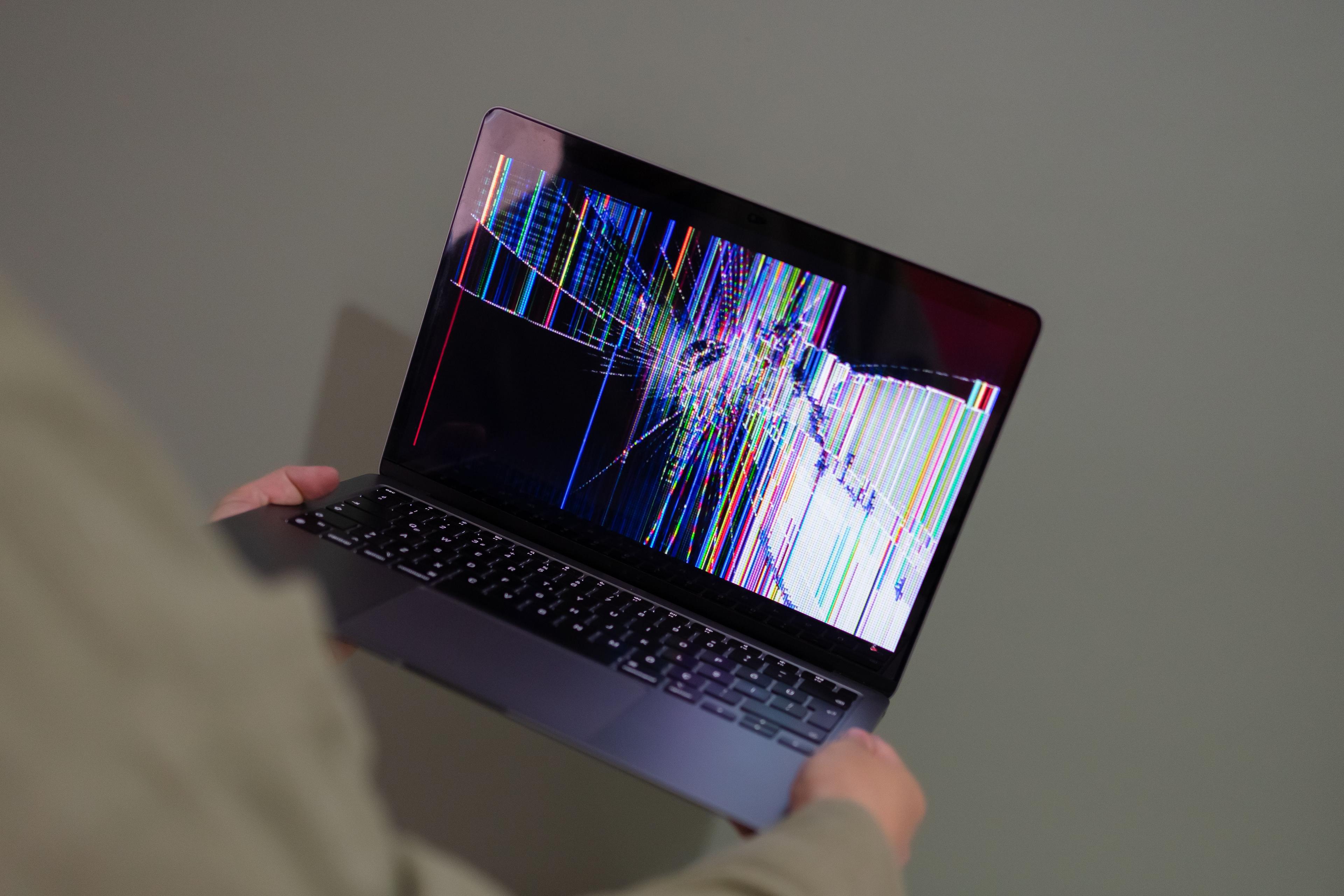 Close-up of a MacBook screen showing a dark pressure blotch near one edge while the aluminum lid looks undamaged